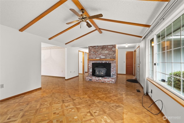 unfurnished living room featuring lofted ceiling with beams, ceiling fan, a wood stove, and a textured ceiling