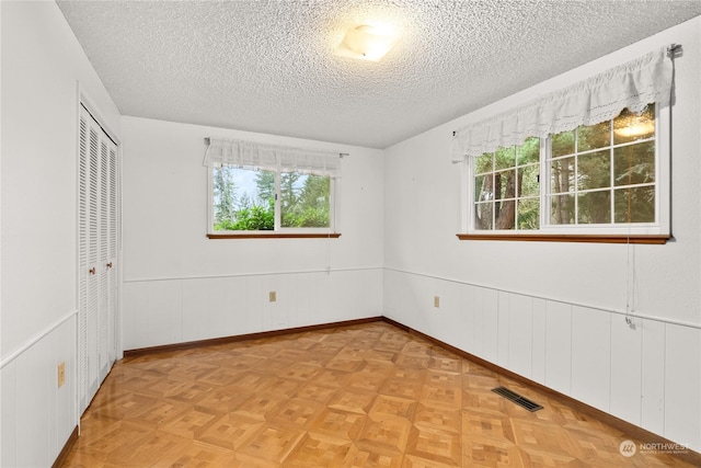 unfurnished bedroom with a closet, a textured ceiling, and light parquet flooring