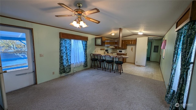 kitchen with light carpet, a kitchen breakfast bar, kitchen peninsula, plenty of natural light, and lofted ceiling