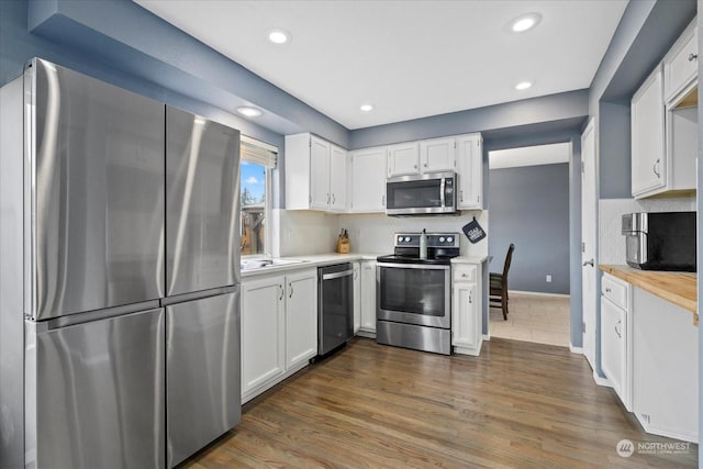 kitchen with backsplash, stainless steel appliances, dark wood-type flooring, sink, and white cabinets