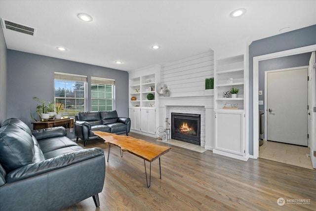 living room with built in shelves and hardwood / wood-style floors