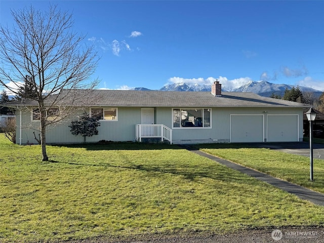 view of front of house featuring a front lawn, aphalt driveway, a chimney, a garage, and a mountain view