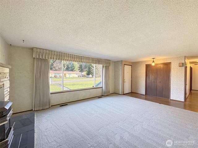 unfurnished living room featuring carpet, visible vents, and a textured ceiling