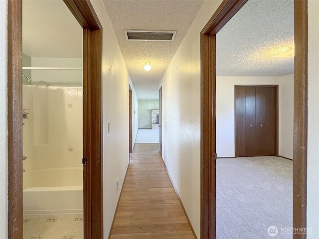 hallway with visible vents and a textured ceiling