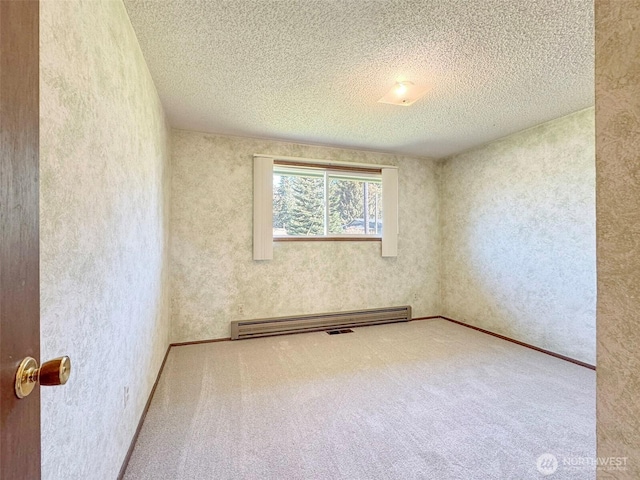 carpeted empty room featuring visible vents, baseboard heating, and a textured ceiling