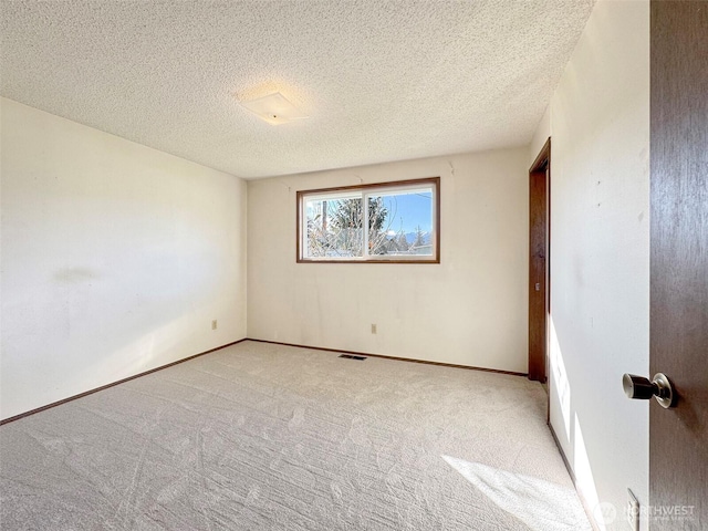 spare room featuring light carpet, visible vents, a textured ceiling, and baseboards