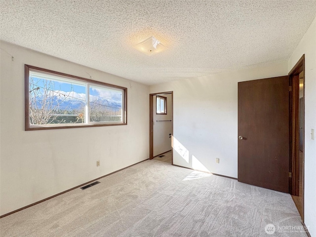 unfurnished bedroom with carpet flooring, baseboards, visible vents, and a textured ceiling