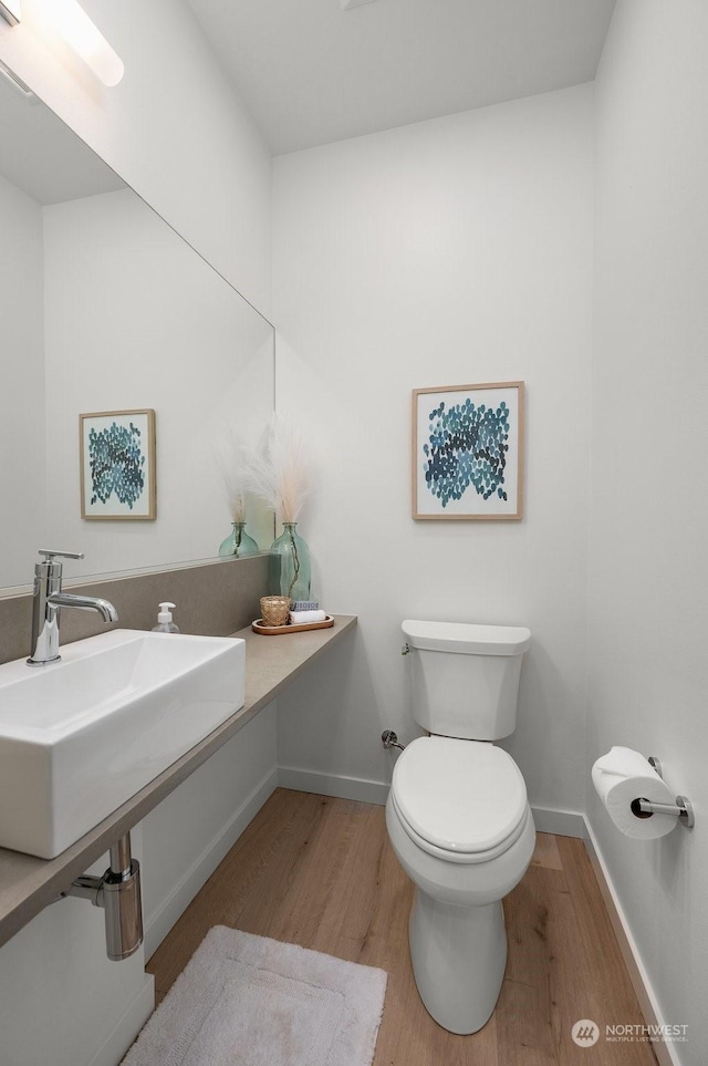 bathroom featuring wood finished floors, a sink, toilet, and baseboards