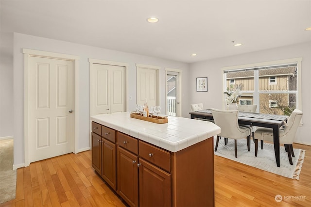 kitchen with tile countertops, a kitchen island, and light hardwood / wood-style floors