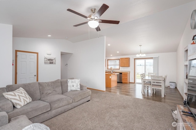 carpeted living room with ceiling fan with notable chandelier, sink, and lofted ceiling