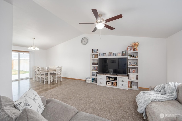 carpeted living room with ceiling fan with notable chandelier and lofted ceiling