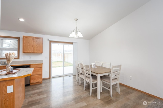 dining room with vaulted ceiling, light hardwood / wood-style floors, and a notable chandelier