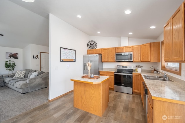 kitchen with vaulted ceiling, stainless steel appliances, light wood-type flooring, a center island, and sink