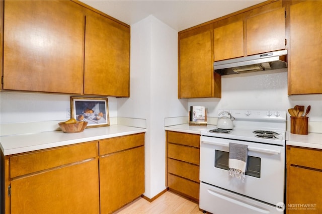 kitchen featuring under cabinet range hood, brown cabinets, white range with electric cooktop, and light countertops