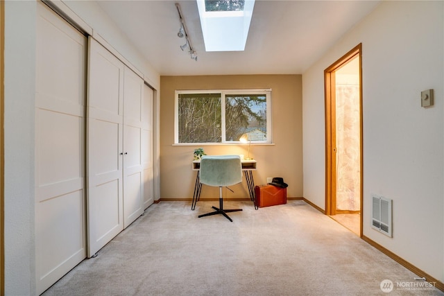 office space with a skylight, visible vents, baseboards, light carpet, and track lighting