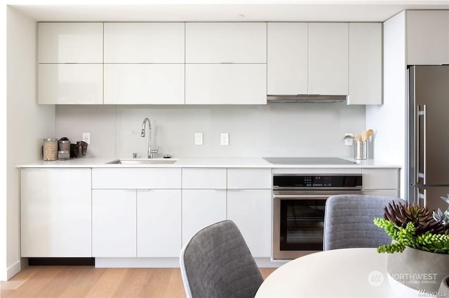 kitchen featuring appliances with stainless steel finishes, light hardwood / wood-style floors, white cabinetry, and sink