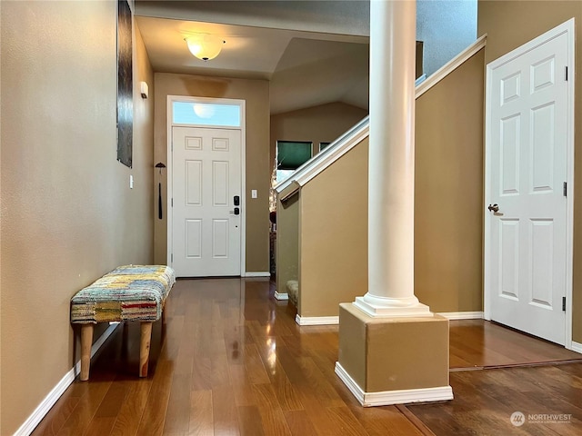 entryway featuring dark hardwood / wood-style flooring, vaulted ceiling, and decorative columns