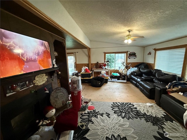 living room featuring ceiling fan, a textured ceiling, and wooden walls