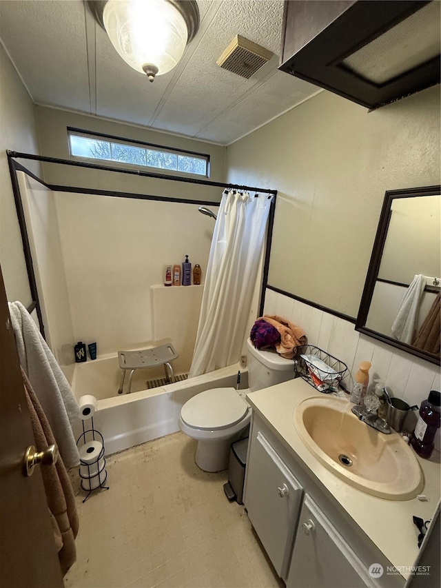 full bathroom featuring shower / bath combination with curtain, toilet, a textured ceiling, and vanity