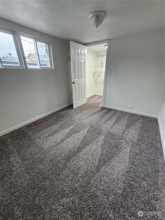 carpeted empty room featuring a textured ceiling and baseboards