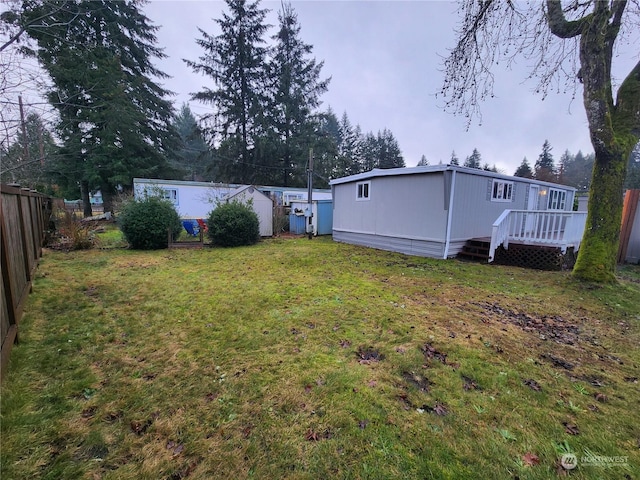 view of yard featuring an outbuilding, a fenced backyard, and a wooden deck