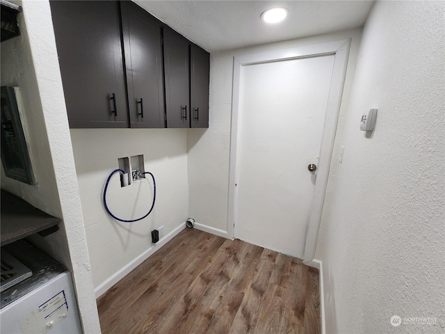 washroom with wood finished floors, cabinet space, baseboards, hookup for a washing machine, and a textured wall