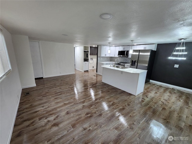 kitchen featuring tasteful backsplash, visible vents, stainless steel appliances, and wood finished floors