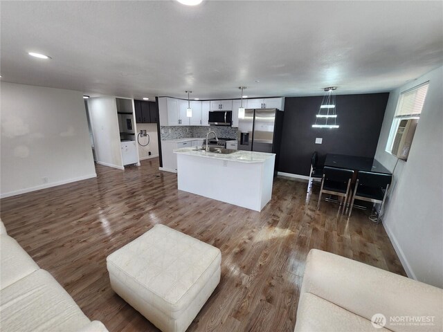 kitchen featuring dark wood finished floors, a sink, light countertops, appliances with stainless steel finishes, and tasteful backsplash