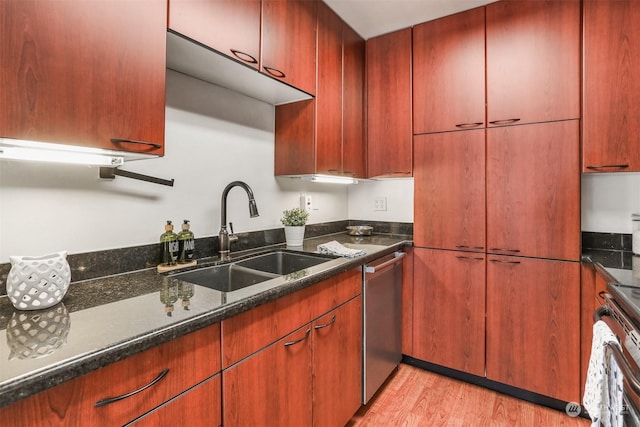 kitchen featuring sink, stainless steel dishwasher, stove, dark stone counters, and light hardwood / wood-style floors