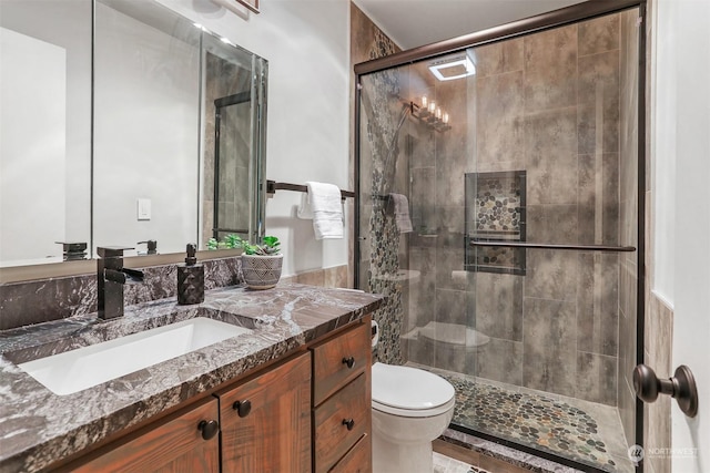 bathroom with vanity, toilet, and a shower with shower door