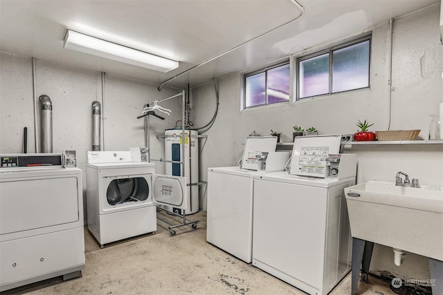 washroom featuring sink, electric water heater, and washing machine and clothes dryer