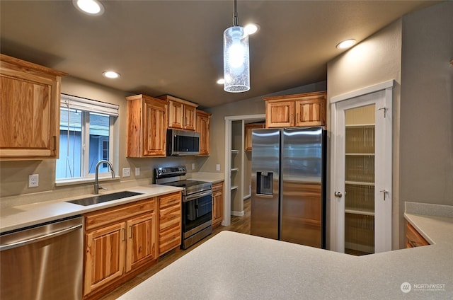 kitchen with pendant lighting, lofted ceiling, sink, appliances with stainless steel finishes, and wood-type flooring