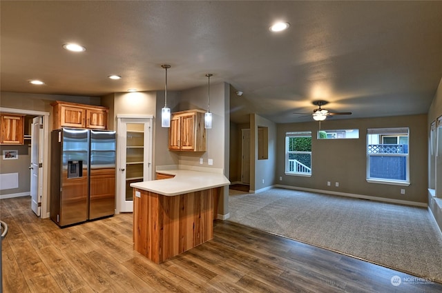 kitchen featuring pendant lighting, lofted ceiling, stainless steel fridge, light wood-type flooring, and kitchen peninsula