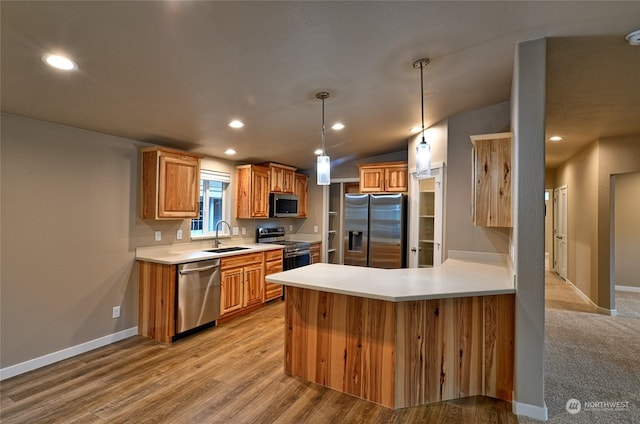 kitchen with sink, hanging light fixtures, stainless steel appliances, light hardwood / wood-style flooring, and vaulted ceiling