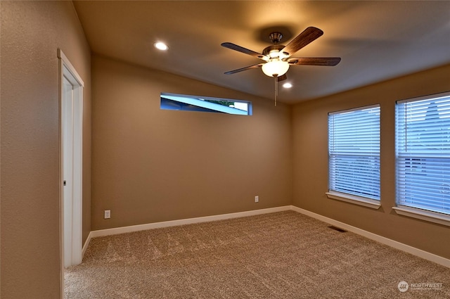 carpeted spare room featuring ceiling fan and vaulted ceiling