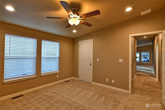 empty room featuring ceiling fan, light colored carpet, and vaulted ceiling