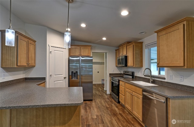 kitchen featuring sink, dark wood-type flooring, stainless steel appliances, pendant lighting, and lofted ceiling