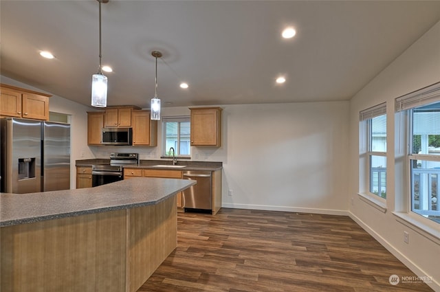 kitchen with appliances with stainless steel finishes, vaulted ceiling, dark wood-type flooring, sink, and decorative light fixtures