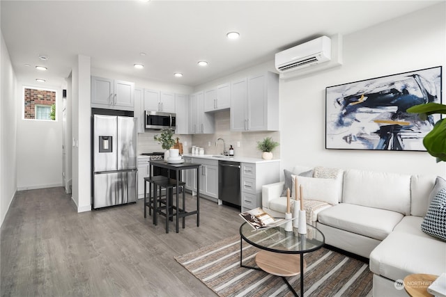 living area featuring light wood-type flooring, baseboards, an AC wall unit, and recessed lighting