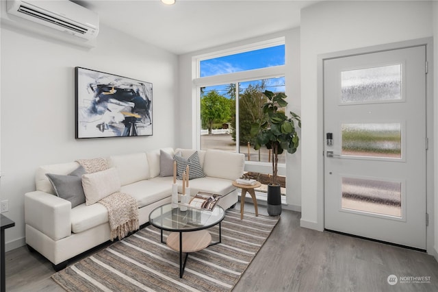 living room featuring baseboards, an AC wall unit, and wood finished floors