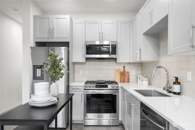 kitchen with a sink, stainless steel appliances, light countertops, and decorative backsplash