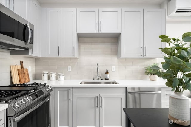 kitchen with backsplash, stainless steel appliances, an AC wall unit, light countertops, and a sink