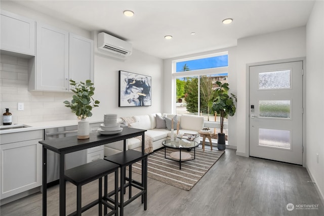 interior space featuring a wall unit AC, light wood-style flooring, baseboards, and recessed lighting