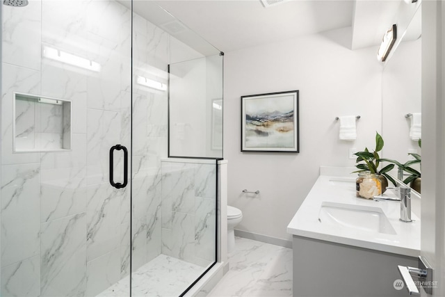 full bathroom with double vanity, a marble finish shower, toilet, marble finish floor, and a sink