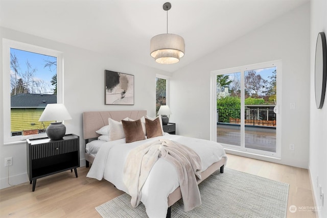 bedroom with light hardwood / wood-style floors, access to exterior, and lofted ceiling