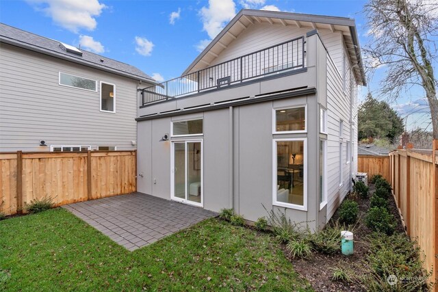 back of property featuring a patio area, a balcony, and a yard