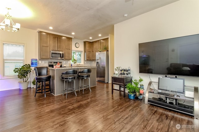 kitchen featuring a breakfast bar, dark hardwood / wood-style floors, light stone countertops, decorative light fixtures, and stainless steel appliances