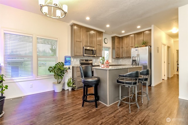 kitchen featuring backsplash, pendant lighting, a breakfast bar area, a kitchen island, and appliances with stainless steel finishes