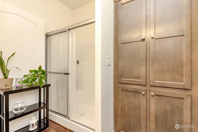 bathroom with hardwood / wood-style floors and an enclosed shower