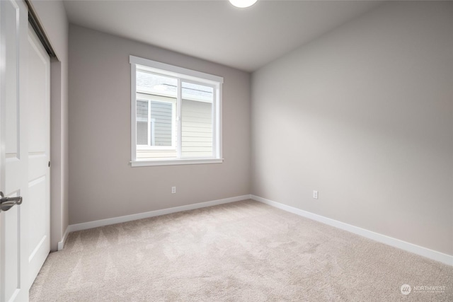 unfurnished bedroom with light carpet, a closet, and baseboards